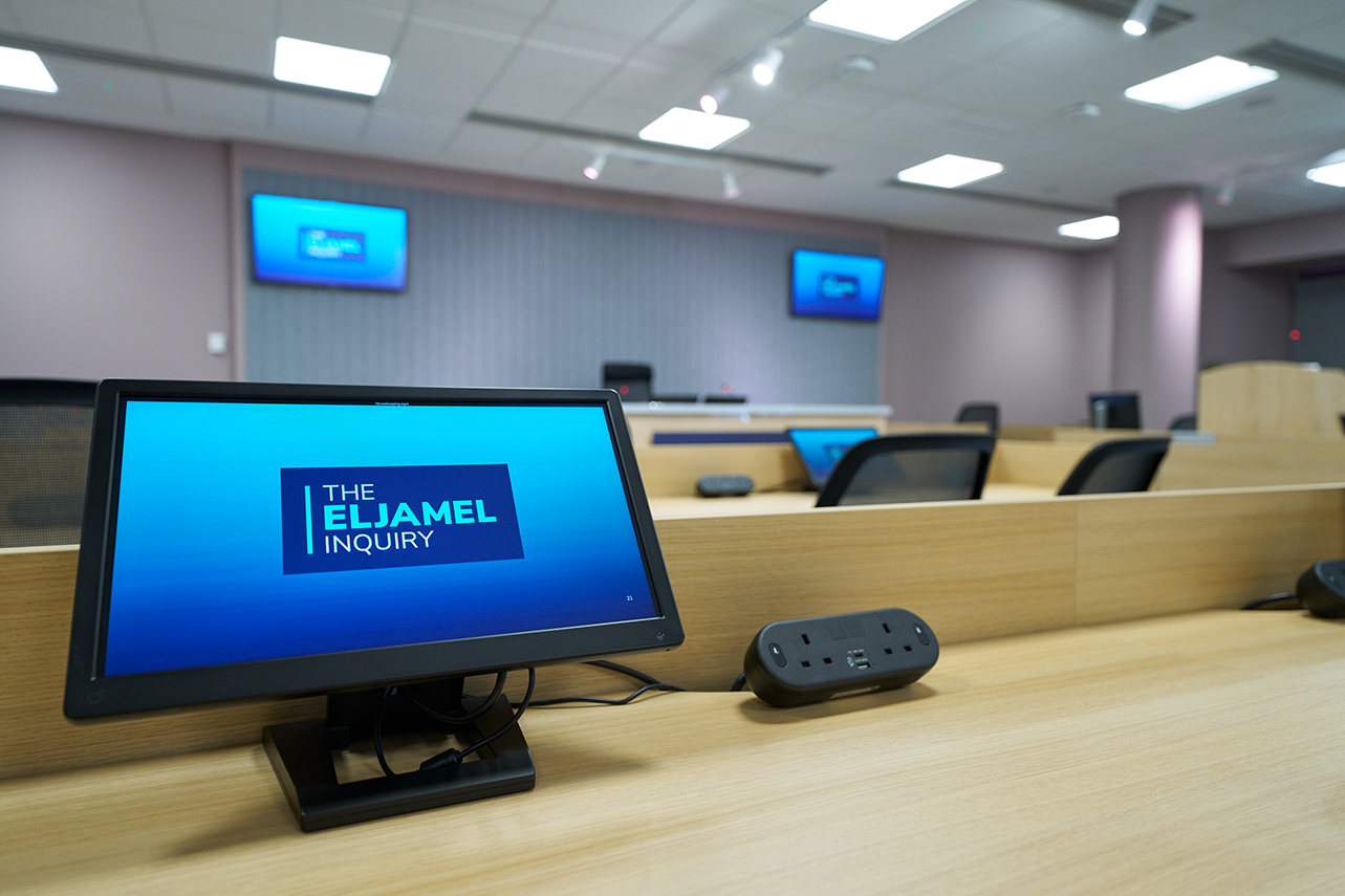 Computer and television screens inside the hearing suite display the Eljamel Inquiry logo
